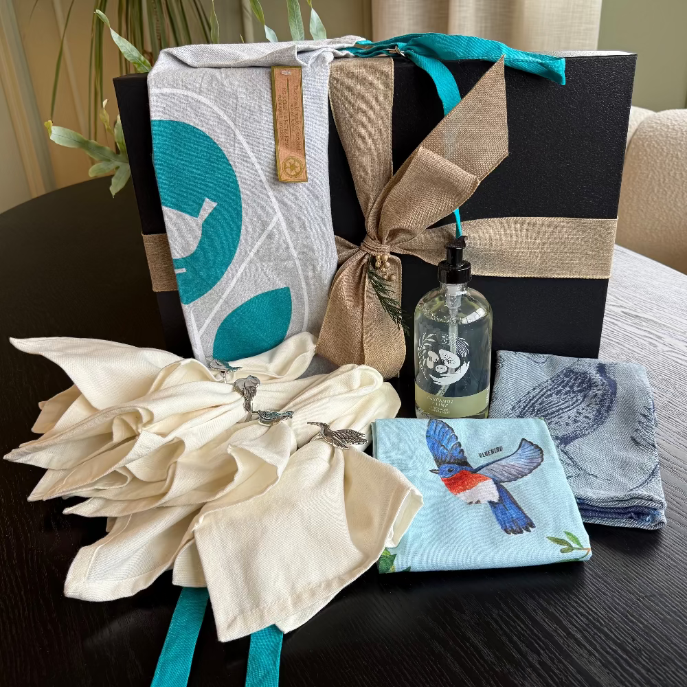 Gift basket with decorative items including a bottle, napkins, and towels on a table.