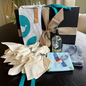 Gift basket with decorative items including a bottle, napkins, and towels on a table.