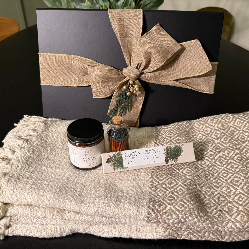 Gift set with black box, candle, and bottle  of matches on a textured blanket