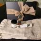 Gift set with black box, candle, and bottle  of matches on a textured blanket