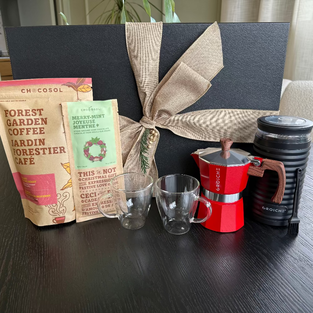 Gift basket with coffee-themed items including a coffee bag, mugs, and a coffee maker on a wooden surface.
