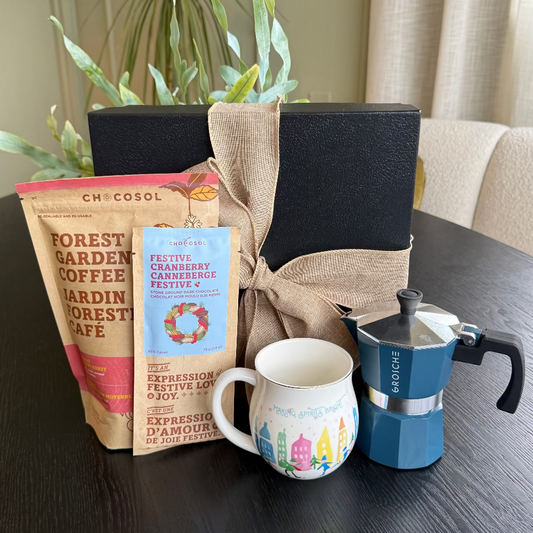 Coffee-themed gift set with coffee package, mug, and espresso maker on a table.
