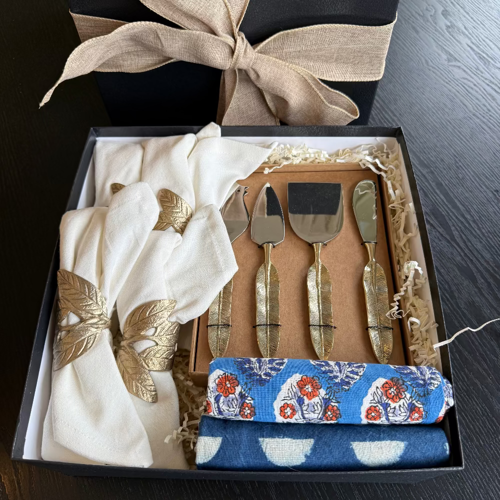 Gift set with cheese knives, cloths, and a bow in a box on a dark surface
